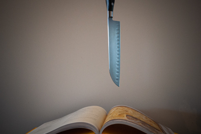 This knife is falling in a recipe book. This was made with a fast shutter speed to snap the movement in time.